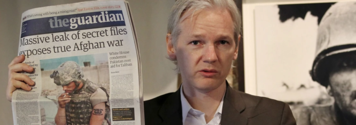 Julian Assange of WikiLeaks holds up a copy of The Guardian newspaper as he speaks to reporters