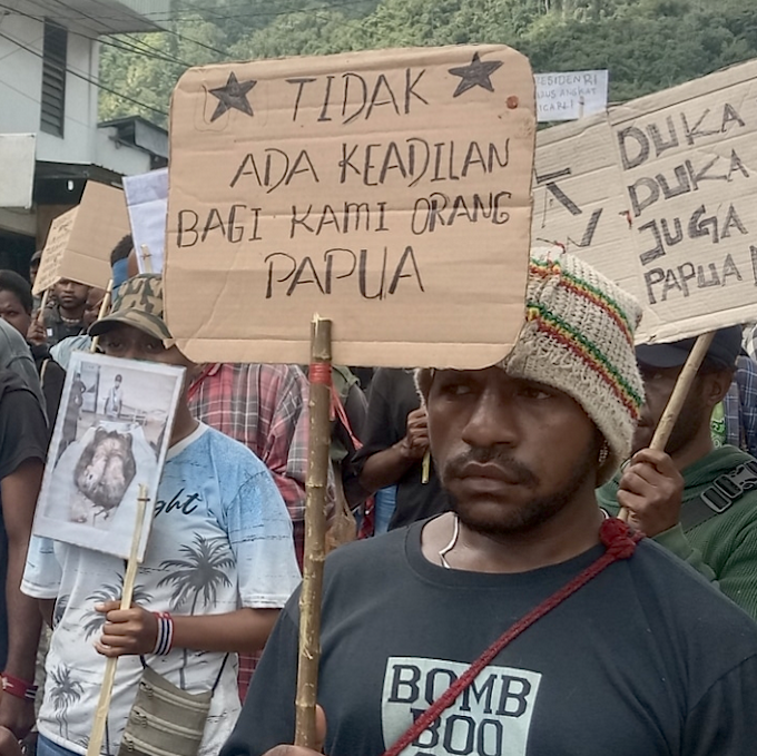 West Papuan demonstrators carry posters depicting torture