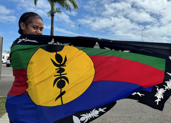 A woman wrapped in the Kanak flag of independence with pride