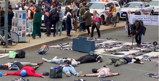 Protesters pose as Palestinian media casualties in Gaza surrounded by blue press protective jackets