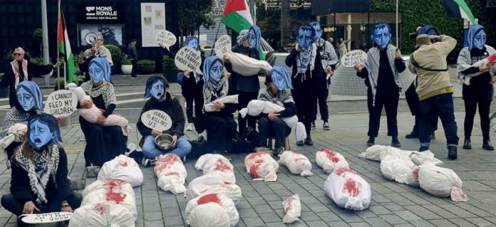 Starvation masks, banners, placards and mock bodies make a dramatic street theatre scene in Auckland’s Takutai Square today in protest over Israel’s genocide against Palestinians in Gaza. Image: Del Abcede/APR