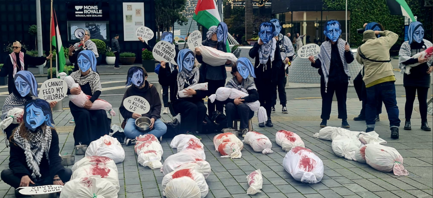 Starvation masks, banners, placards and mock bodies make a dramatic street theatre scene in Auckland’s Takutai Square today in protest over Israel’s genocide against Palestinians in Gaza