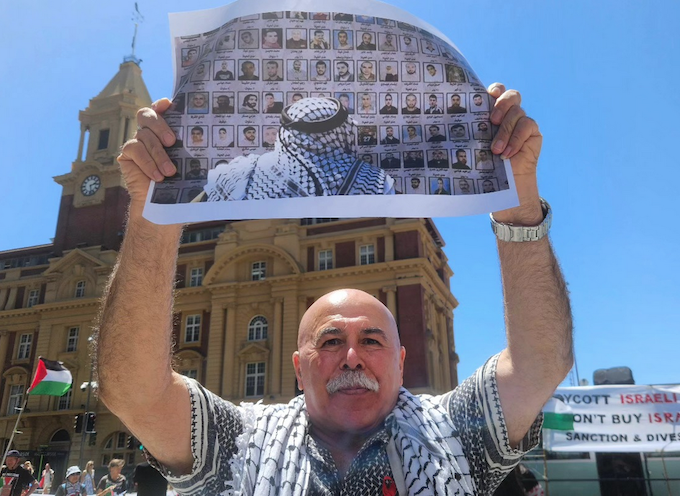 Protester Dr Faiez Idais holds up photographs of some of the thousands of Palestinian detainees held in Israeli prisons at today’s rally in Auckland