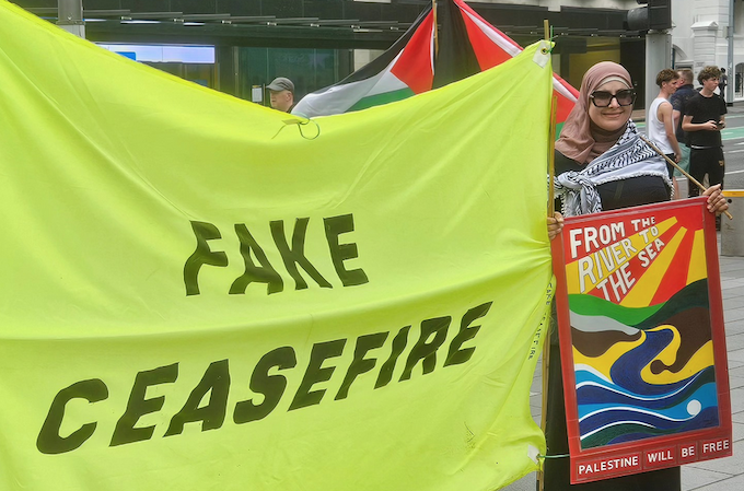 An Auckland protester with a “fake ceasefire” banner